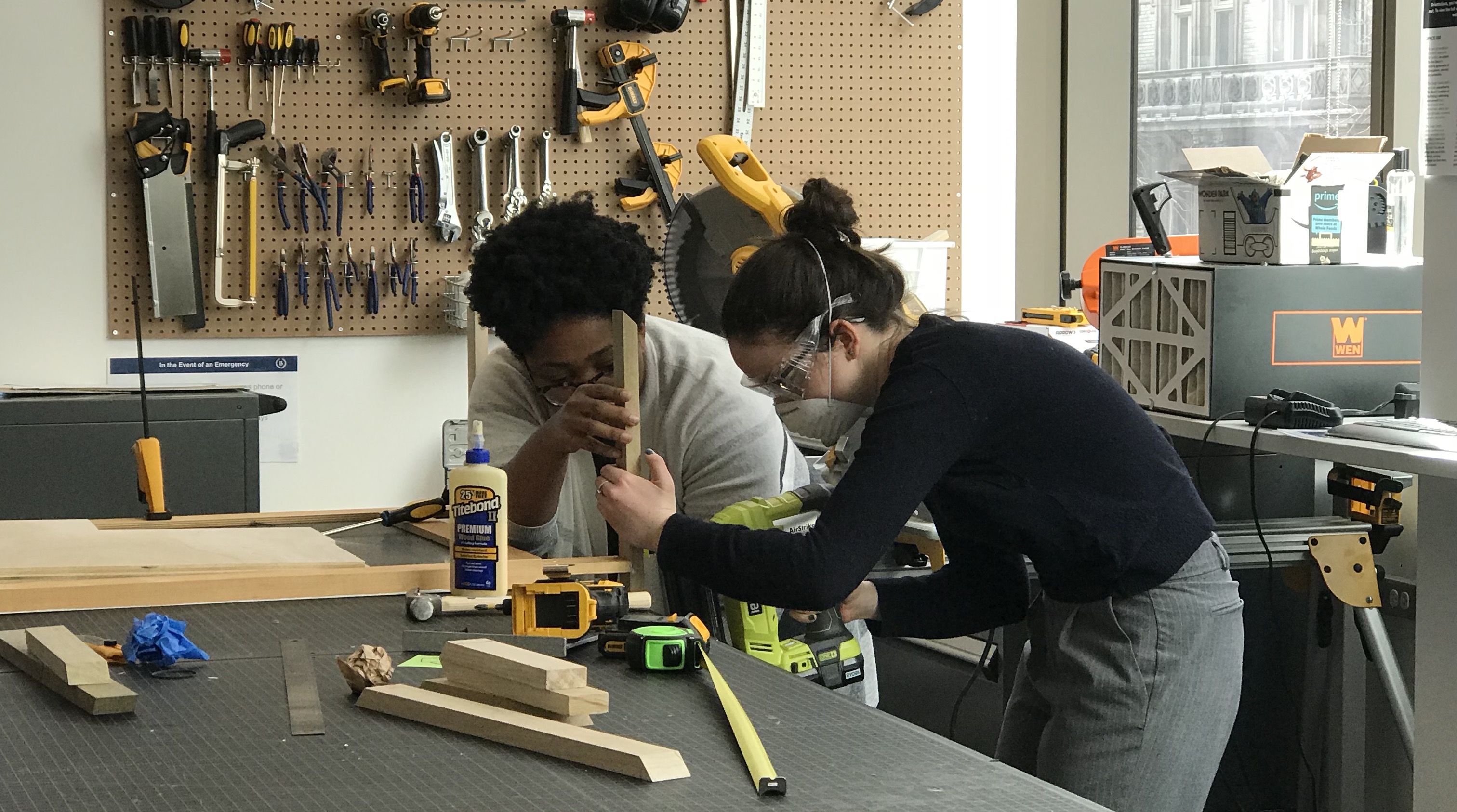 two people wearing safety goggles and using woodworking tools
