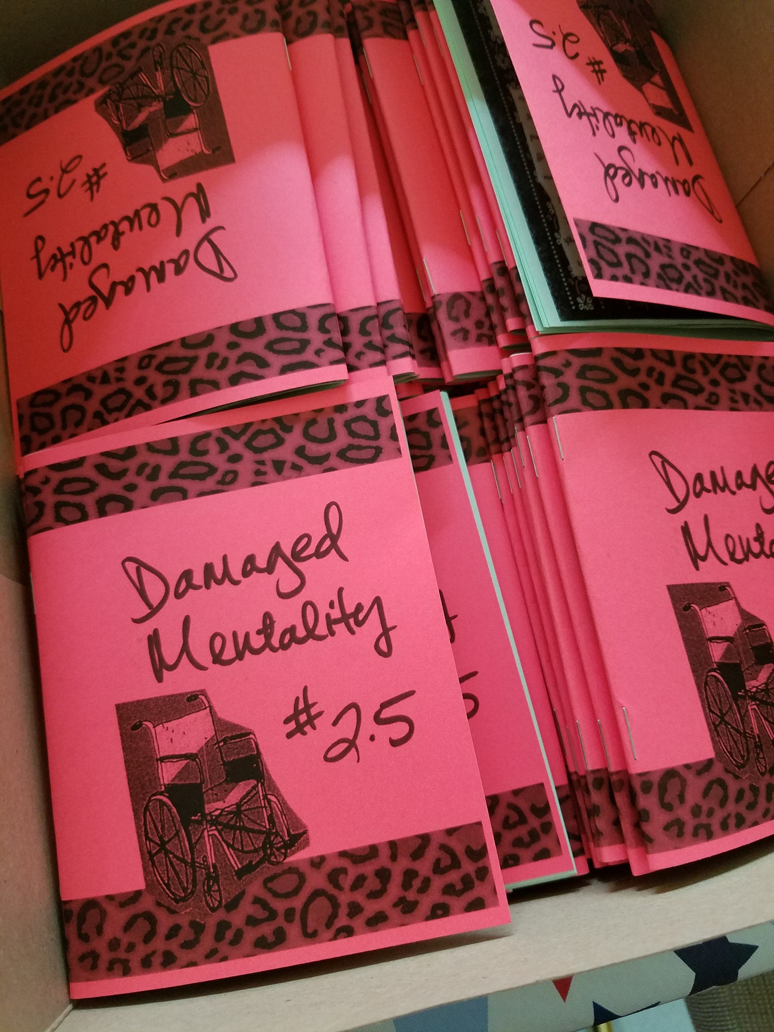 photo of zines: pink cover with clip art wheel chair