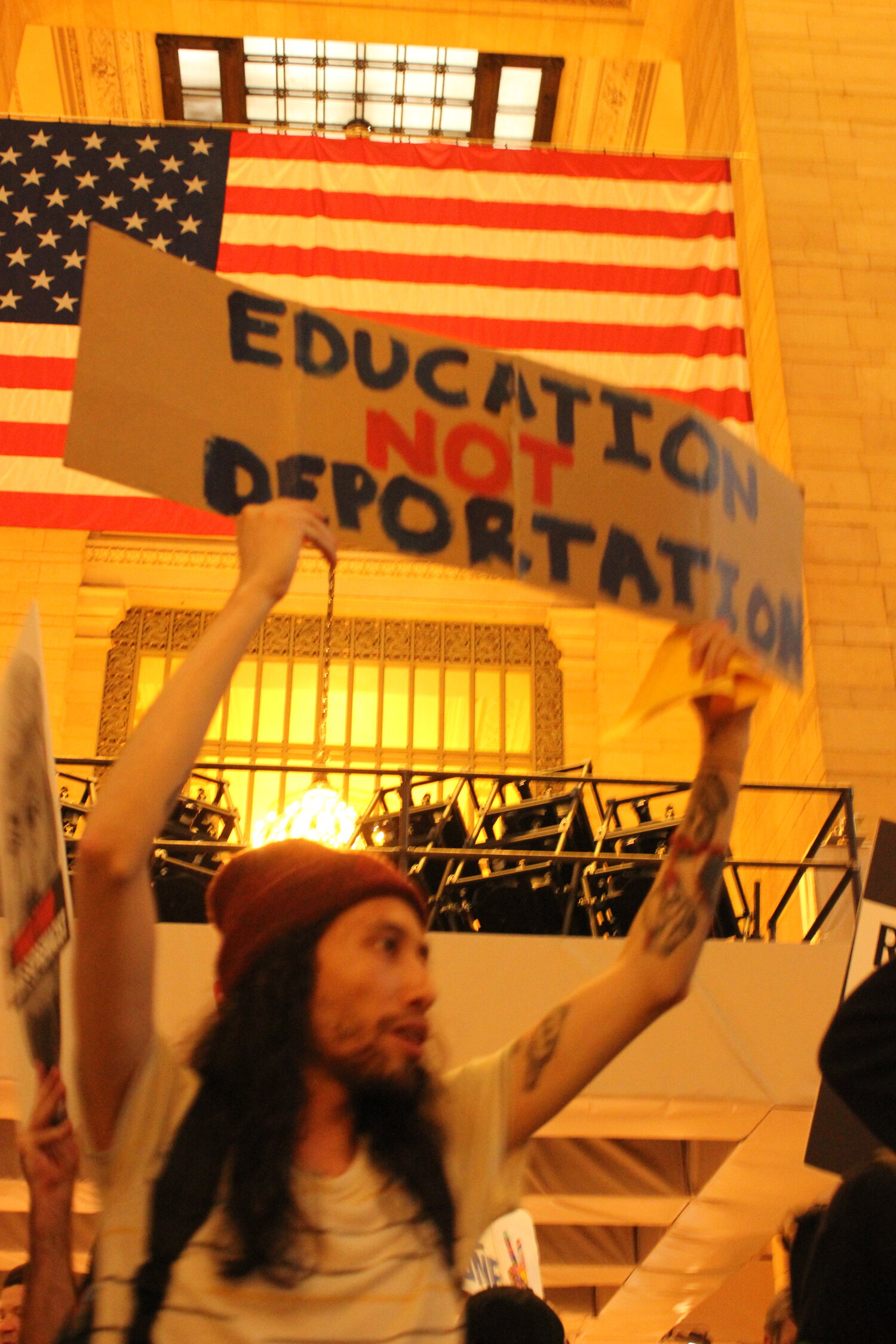 photo of aperson holding a protest sign that reads "Education Not Deportation"