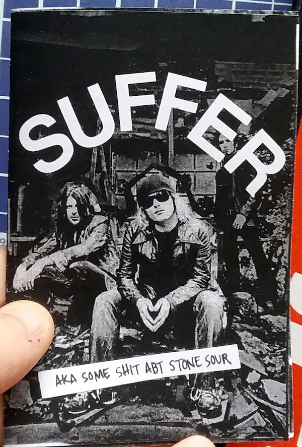 photo of pale thumb holding zine, which depict members of the band Stone Cold collaged onto a dark background