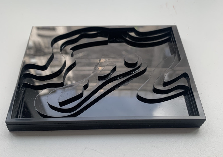 small rectangular black acrylic that is laser cut and layered to look like the surface of Mars.