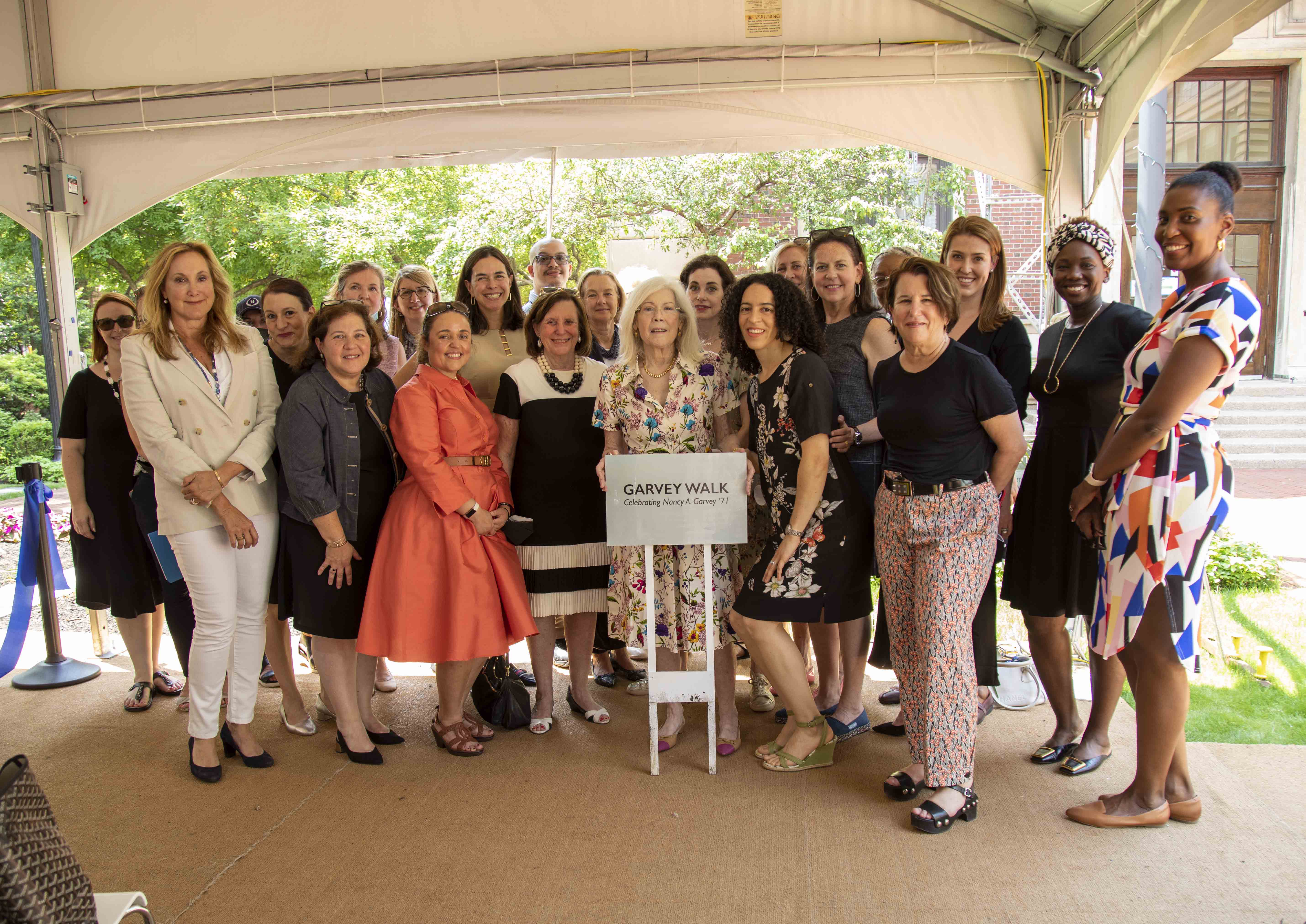 Nancy Garvey '71 holding the new "Garvey Walkway" sign, surrounded by friends, family, Barnard staff, and trustees