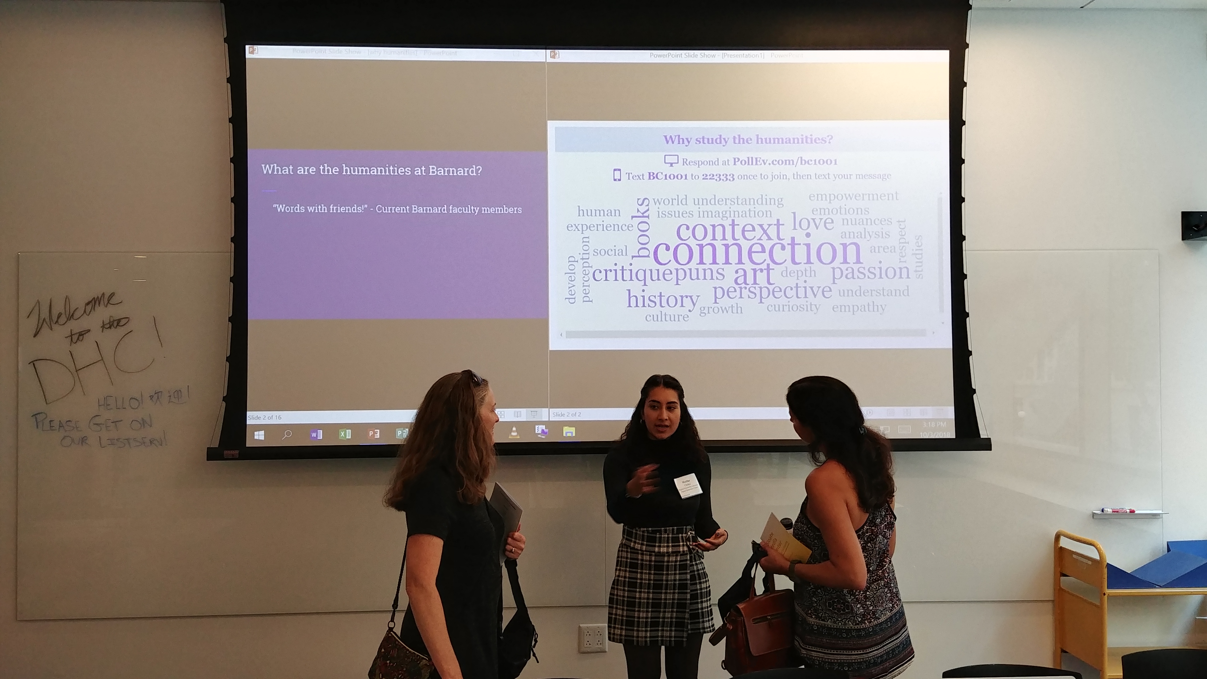 People talking in the DHC, with a digital word cloud displayed in the background