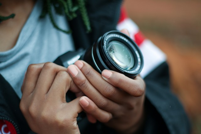 A photographer's hands holding the lens and body of a camera.