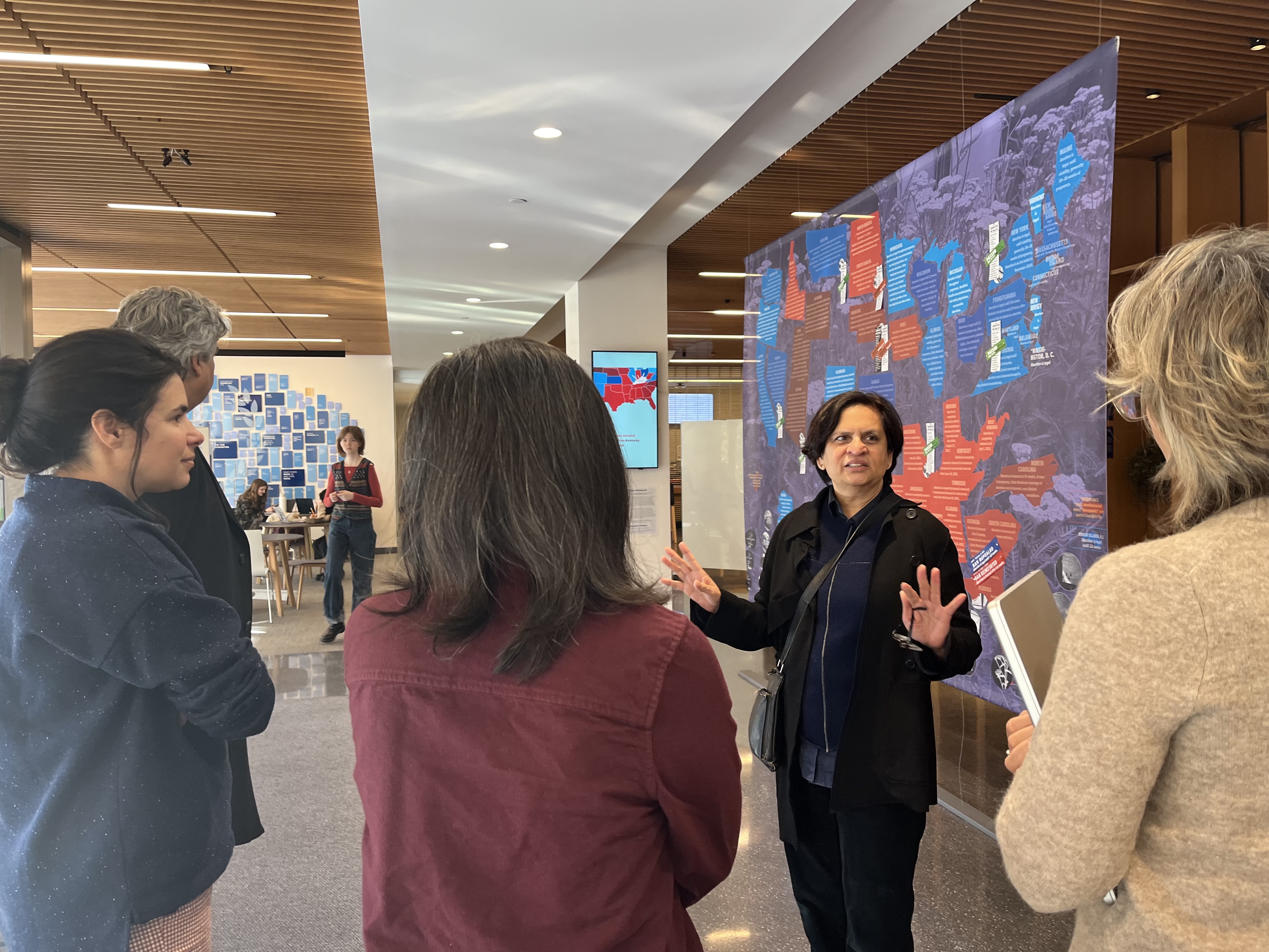 Kadambari Baxi talks to a small group in the Milstein Lobby in front of Trigger Planting