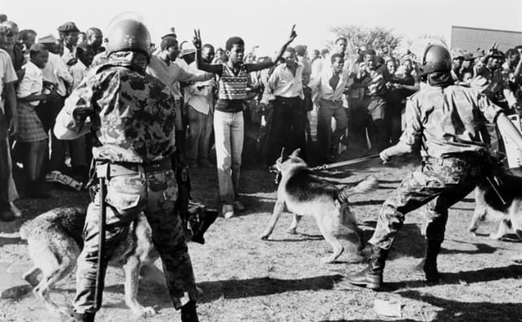 photograph of security forces with dogs hold back crowd protesting against Minister Piet Koornhof being given 1980
