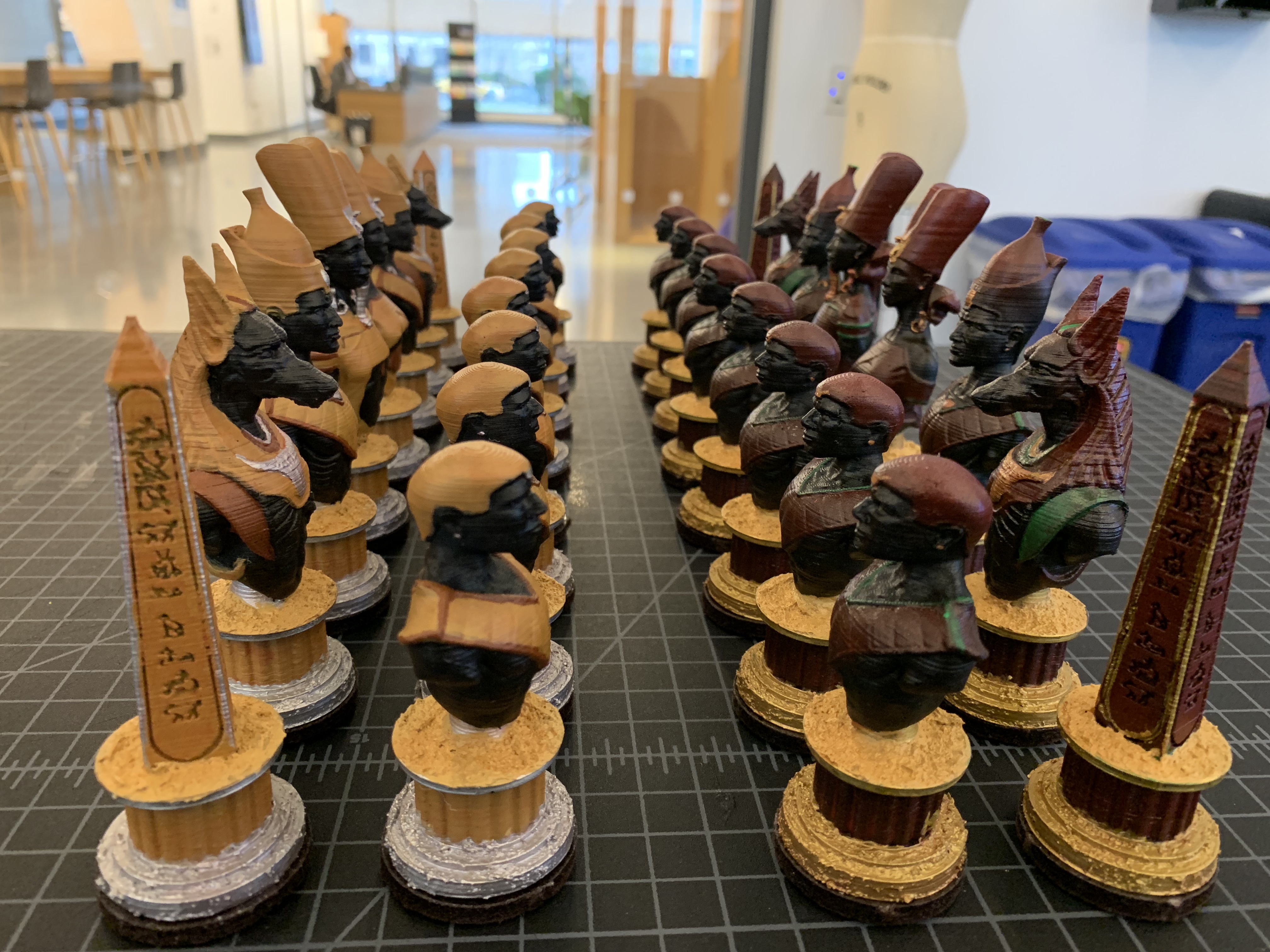 The completed chess pieces are arranged in four rows. The opposing sides face each other.