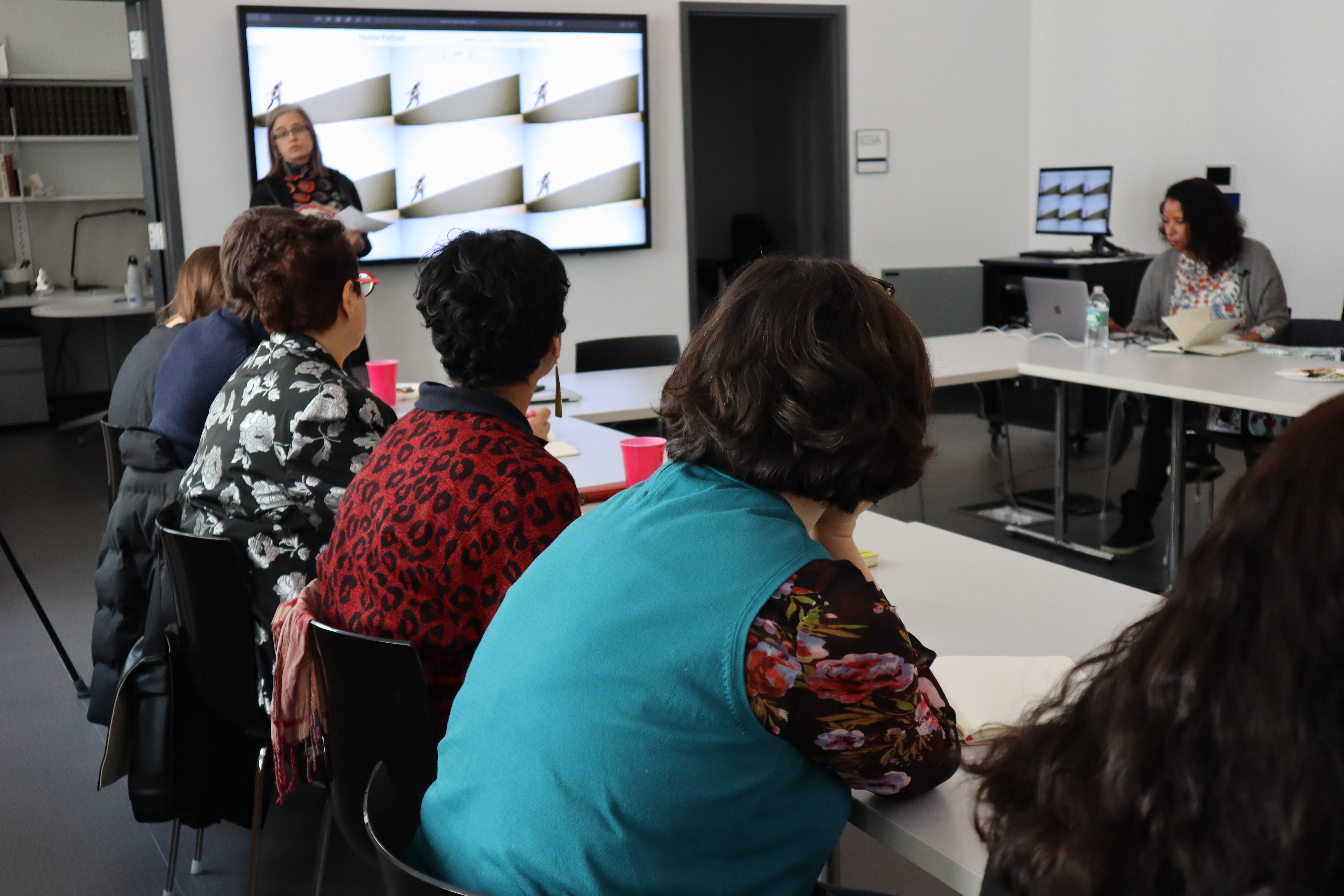 DHC Interim faculty director Janet Jakobsen introduces Professor Parham, standing before a screen displaying her website while event attendees look on.