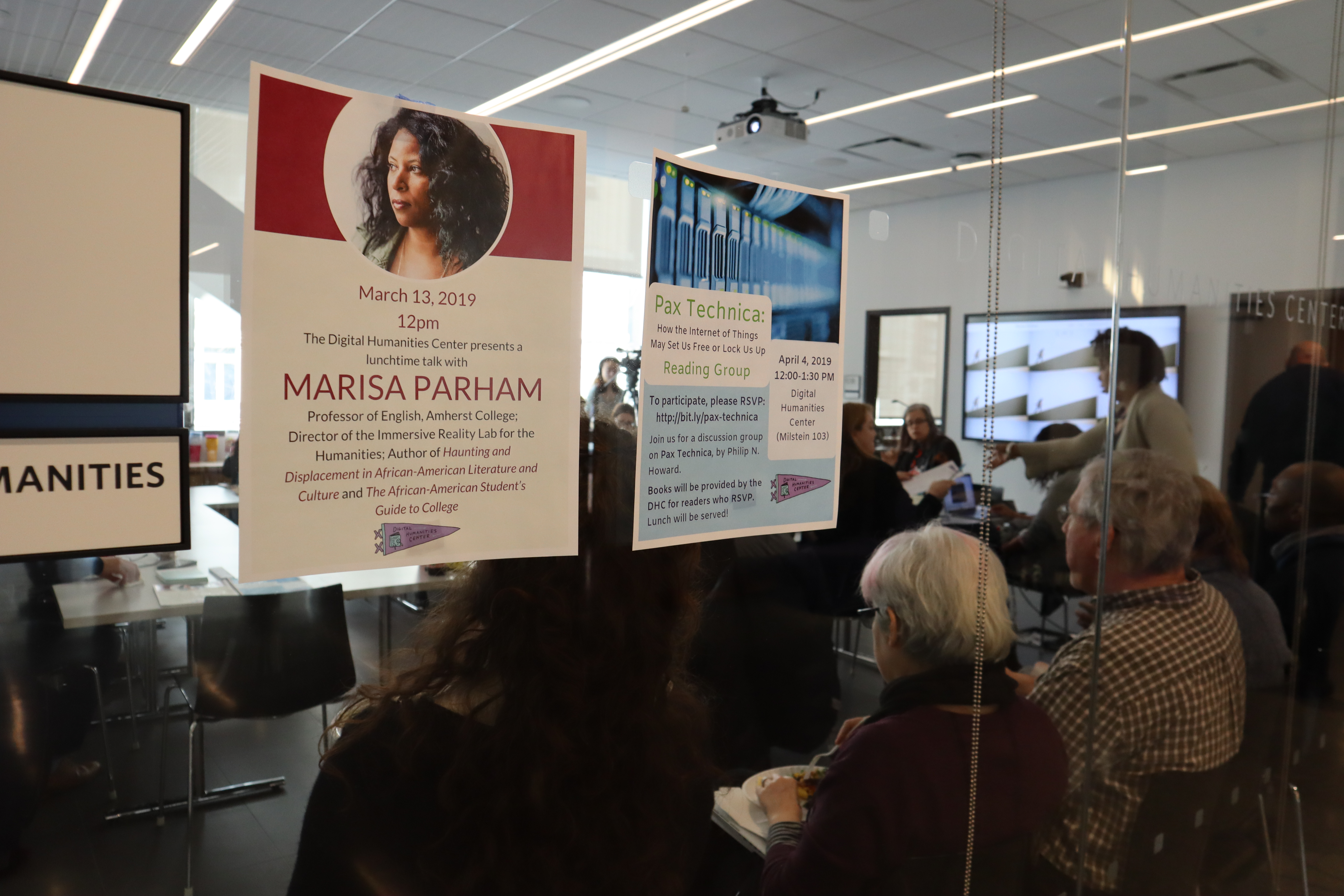 A view from outside the DHC, with the flier for Professor Parham's lecture up on the glass wall, and the attendees visible through it.