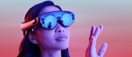 A woman wears a magic leap headset and feels the space in front of her with her hands.