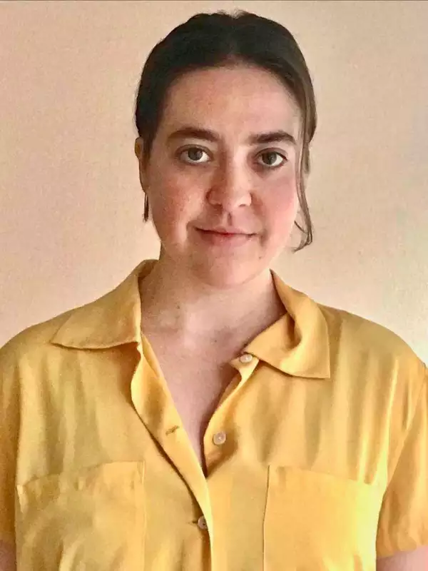 Woman with brown hair wearing a yellow shirt