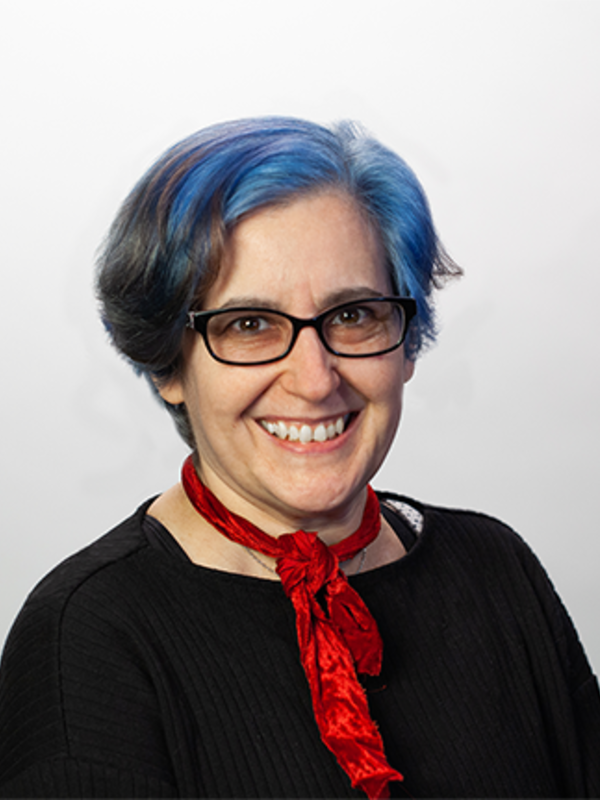 photo of white woman with brown and blue hair, glasses, black shirt, red ribbon around her neck