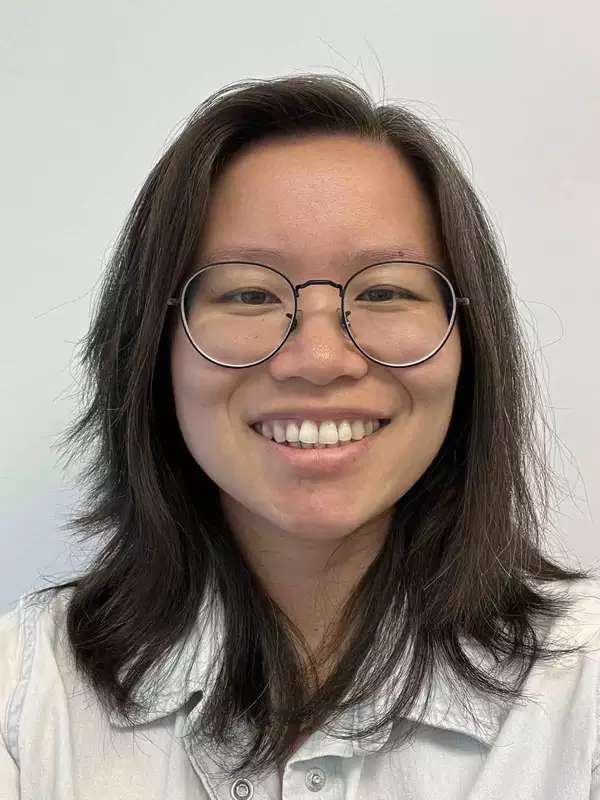 Woman with medium-length dark hair wearing glasses and a white shirt