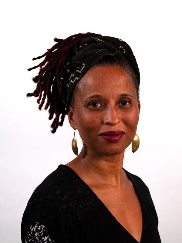 Portrait of a brown skinned woman with locs facing forward