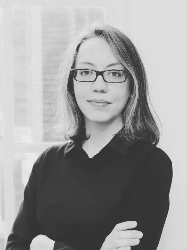 Black and white headshot of woman with medium-length hair wearing a dark shirt and glasses