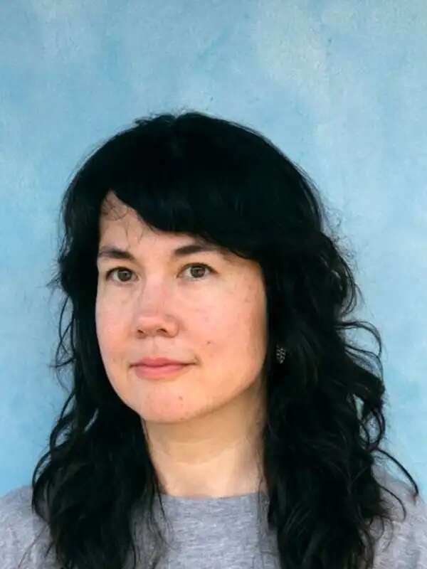 Woman with dark hair, wearing grey shirt