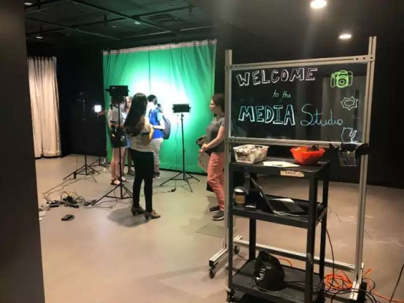 Media studio. Students stand near a green screen and cameras.